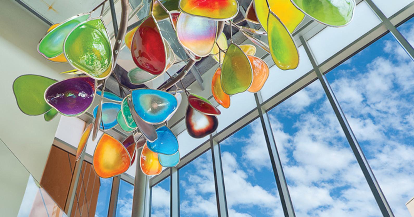 天花板上悬挂着一个雕塑，就像用彩色玻璃制作的树枝和树叶.